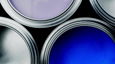 Open multicolor paint cans on grey background, top view