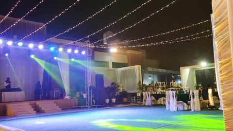 Delhi, India - circa 2020 : locked shot of an indian wedding venue with dance lights moving on a dance area with a stage and a DJ console behind it. Weddings in Delhi are very opulent with amazing