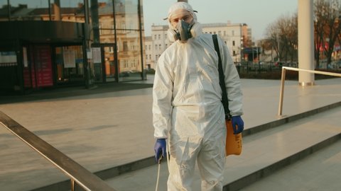 Man, worker disinfects, sprays chemicals on surface against coronavirus. Sanitary measures in public place during quarantine