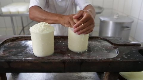 Close up of man's hand squeezing rennet milk in the form of plastic to make the famous artisan cured cheese from Minas Gerais on a white cotton cloth. Concept of gourmet, food, cook, healthy, organic 