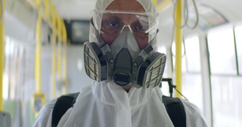 Portrait of HazMat team member in protective suits posing a bus during virus outbreak. Coronavirus, COVID-19