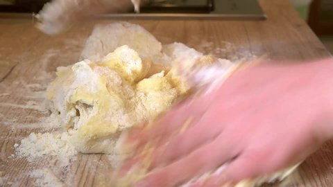 Close up of caucasian white woman making homemade gnocchi dough on a wooden table at home.