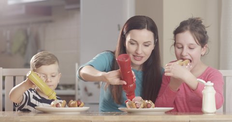 Cooking Hotdog at the Kitchen Table where Mother Having Fun with Son and Daughter shot on Red Camera