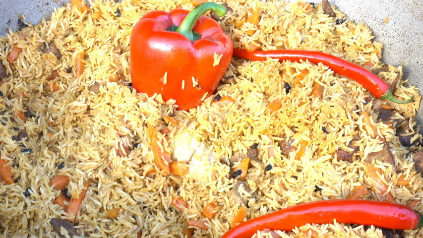 Cooked delicious pilaf with red pepper in a large cauldron. Close-up