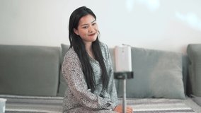 Chinese girl influencer talking to followers on social media. China woman at home recording vlog video on smartphone. Internet celebrity vlogging with cell phone.