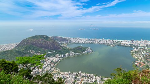 Aerial panorama timelapse of Rio de Janeiro, Brazil. View of Ipanema, Leblon, Lagoa lake, Copacabana, the beach and the ocean. Moor peak and mountains in the background. Jungle tree in front.