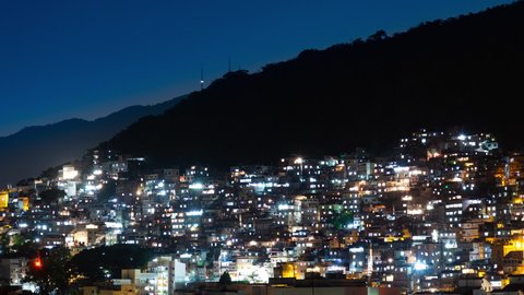 Night Aerial timelapse of Babilonia favela shanty town in Copacabana, Rio de Janeiro, Brazil. Evening view of the hill with houses and lights.  Morro and mountain in the background. 