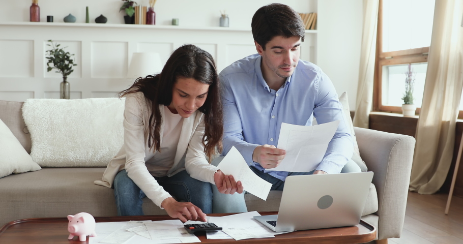 Young couple calculating bills, taxes and expenses, counting mortgage rate making savings concept. Millennial husband and wife considering taking bank loan, investing money. Family financial economy. Royalty-Free Stock Footage #1048785283