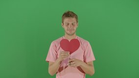 heartbroken adult man cutting a paper heart studio isolated shot against green screen background
