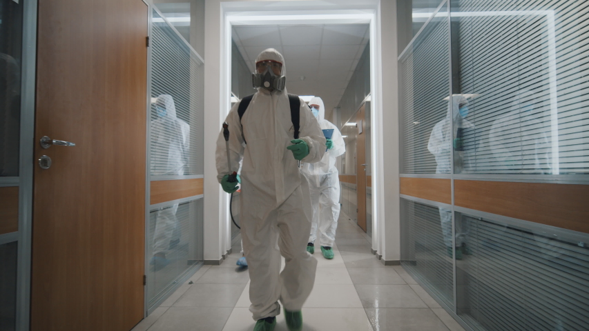 Fighting covid-2019 three men in protective suits carrying equipment and examining building after disinfection against coronavirus. Specislists disinfecting empty office during coronavirus quarantine | Shutterstock HD Video #1048795978