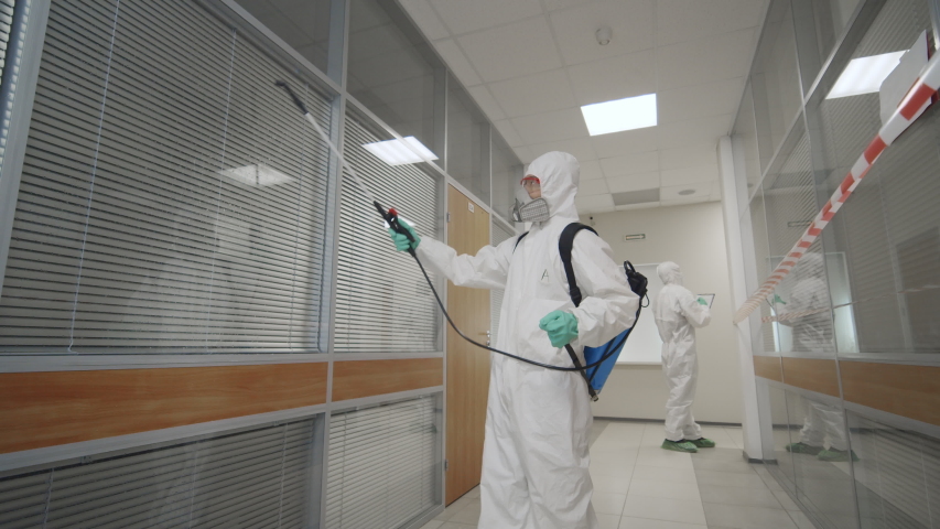 2019-ncov spreading, coronavirus outbreak. Team of virologists in protective coveralls and masks working in office building disinfecting rooms fighting against coronavirus spread. Royalty-Free Stock Footage #1048795996
