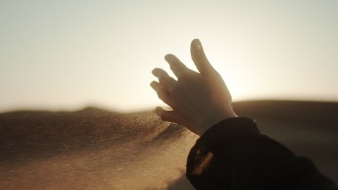 Close-up hand signs with handful of sand. Sand from the desert spills out of the girl’s hand. 4K Slow Motion