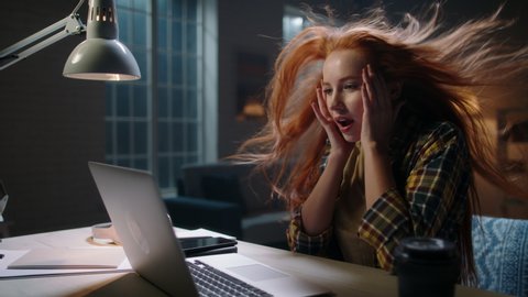 Positively surprised redhead caucasian girl looking at laptop, wing blowing her hair. Model reading breaking news, getting an amazing discount during online shopping or shocked by event 4k footage