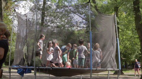 Many children jump on a trampoline in a city park. Germany, Munich 10. June. 2019. Children jumping on a trampoline outside in the summer.