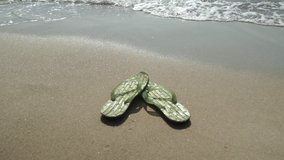 Men's slippers on the beach washed by water