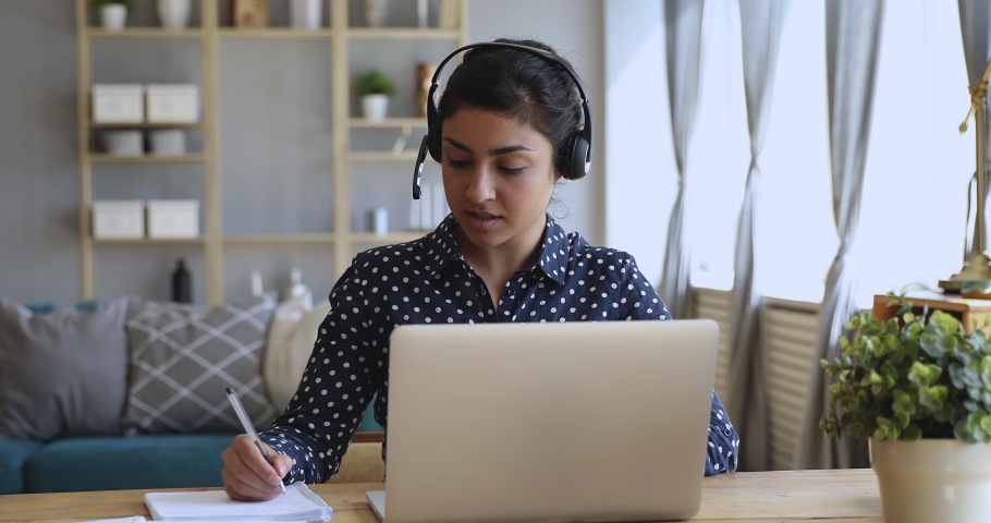 Focused millennial hindu professional financial advisor wearing headset, holding video call support services with customer. Motivated concentrated young indian student studying on online courses. Royalty-Free Stock Footage #1048820536
