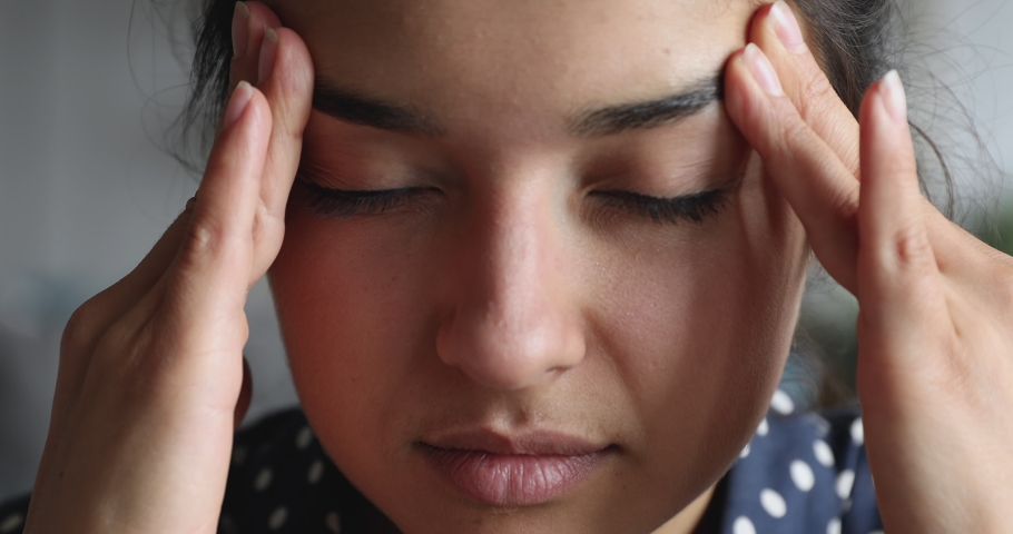Close up exhausted frustrated young indian woman massaging nose bridge temples. Stressed unhealthy millennial mixed race girl feeling tired suffering from migraine, panic attack, high blood pressure.