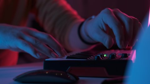Male hands playing on piano electronic keyboard. Fingers tapping drum pads midi controller. Musician producing song at home recording studio. Sound maker create music melody. Online education. Closeup