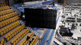 Installation of professional sound, light, video and stage equipment for a concert in a sports hall. Stock footage. Stage lighting equipment is clamped on a truss for lifting.