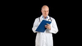 Male doctor in white coat writing on clip board on black background. Practitioner writing medical notes in clip board in dark studio. Medical worker posing front camera
