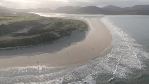Aerial 4k drone shot of Luskentyre Beach during sunny day. Beach located in Lewis and Harris island in Scotland. Beautiful waves hitting beach.