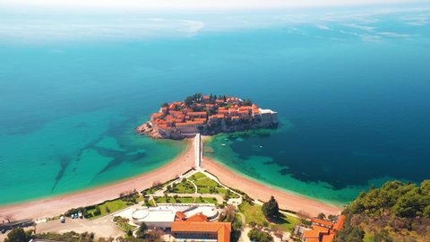 Sveti Stefan, Montenegro. Aerial above view of the Sveti Stefan island. Amazing turquoise Adriatic sea. Drone flying over buildings with red roofs.  Video Stok