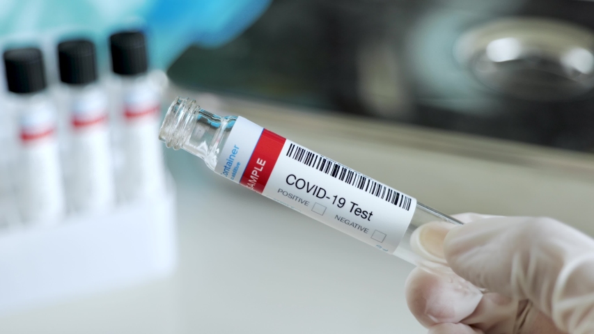Nurse closing a sample tube testing for presence of coronavirus. Tube containing a swab testing for COVID-19. | Shutterstock HD Video #1048835410