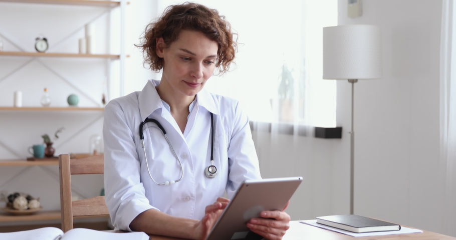 Happy female professional doctor using digital tablet in hospital. Smiling young woman physician holding modern tech pad device working in medical office. Healthcare technology and medicine concept Royalty-Free Stock Footage #1048839259