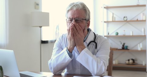 Worried upset senior old adult male doctor feels depressed regrets medical malpractice sitting alone in office. Desperate sad elder surgeon thinking of grief, suffering from burnout or guilt concept.