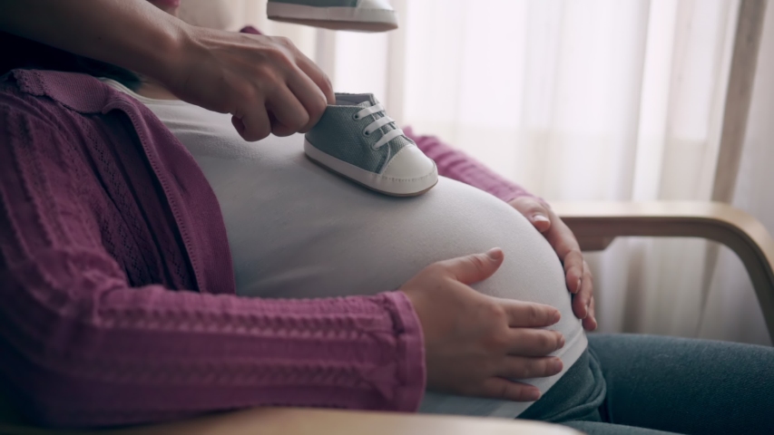 Pregnant couple of husband and wife feels love and relax at home. Young expecting woman holds baby in pregnant belly. Father take care of pregnant mother. Concept of maternity and pregnancy care. | Shutterstock HD Video #1048842256