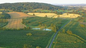 Aerial footage over green fields, hill and a road in United Kingdom.