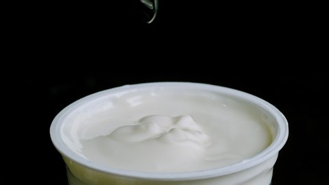 slow motion of a teaspoon sinks into a jar of yogurt 
