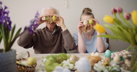 Happy Easter - cheerful grandfather and granddaughter play with Easter eggs on Easter