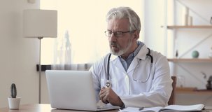 Older doctor talking to patient making video call on laptop. Senior male physician speaking looking at pc screen communicating by webcam in web chat consulting client online. Telemedicine concept