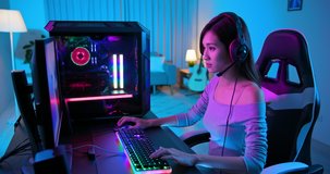 Young Asian Pro Gamer Girl Playing in Online Video Game with rgb keyboard and mouse at home