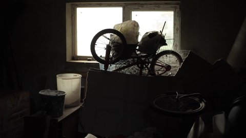 Old things stand on a table in a box against the background of a window in a dark room. Dark silhouette