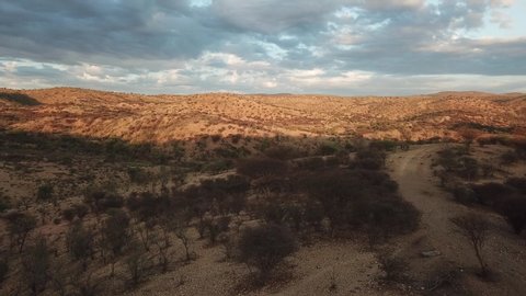 4K aerial drone sunny summer day video African savanna and dry riverbeds surrounded by bush covered hills in Daan Viljoen National Game Park in Khomas Hochland area near Windhoek, Namibia, Africa