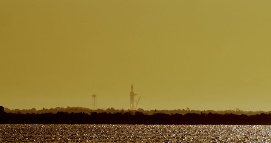 Commercial Space Rocket lifts off from launch pad 39A at Kennedy Space Center to put 60 communications satellites into low-earth orbit. Early morning sunrise with water in foreground. Includes audio