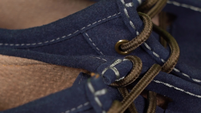Closeup view video of details of casual blue leather mocassins with brown shoelaces.