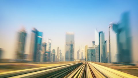 Rushing through the city of Dubai and the desert on the metro, dynamic time lapse footage with view onto the rails