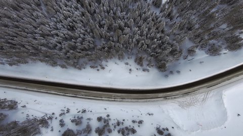Aerial, top down, drone shot over traffic on a slushy road and forest, cloudy day, on Loveland mountain pass, in Colorado, USA