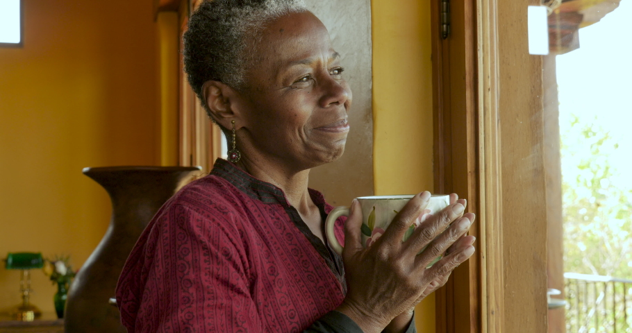 Portrait of a beautiful African American senior black woman in her 60s holding a hot coffee or tea cup, smiling, and looking at camera Royalty-Free Stock Footage #1048901512