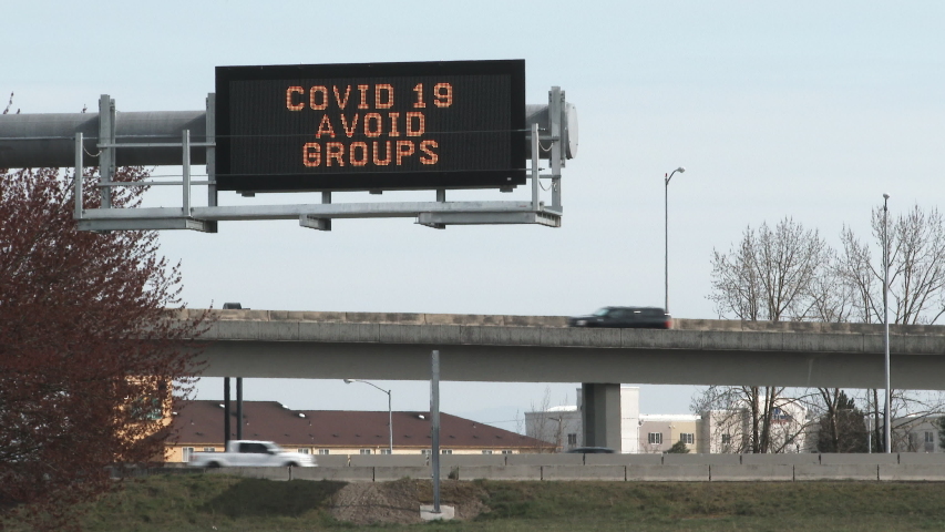 Traffic speeds by on freeway with road sign warning to stay away from groups of people during the COVID 19 crisis. Royalty-Free Stock Footage #1048910140