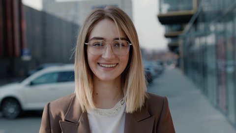 Portrait of stylish attractive caucasian woman in glasses and jacket looking to the camera and smiling happy female spring sunshine lucky sunny day business professional successful