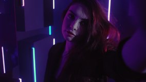 Neon light girl. Party lifestyle. Woman recording video selfie dancing in purple glow.