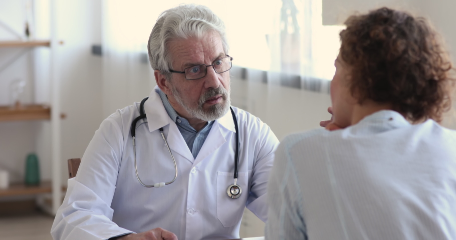 Friendly senior male doctor wear white medic coat consulting female patient joking, laughing at medical checkup visit. Happy old physician gives woman client medicine and healthcare advice concept. Royalty-Free Stock Footage #1048920511