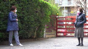  Europe, Italy, Milan, elderly 70-year old ladies with mask speak in the courtyard  building where live keeping the safety distance of one meter,  stay at home during n-cov19 CORONAVIRUS epidemic - Powered by Shutterstock - Get 15% off with code: PIKWIZARD15