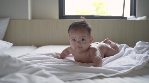 prone baby naked is smile while lying on the bed in the bedroom