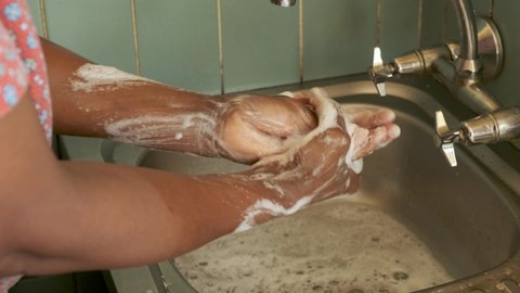 Close up shot of black African woman washing her hands to prevent Covid-19 infection during Coronavirus pandemic. 
