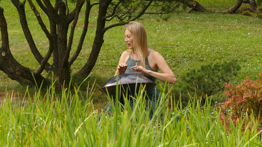 Girl plays in the green field on a hangpan